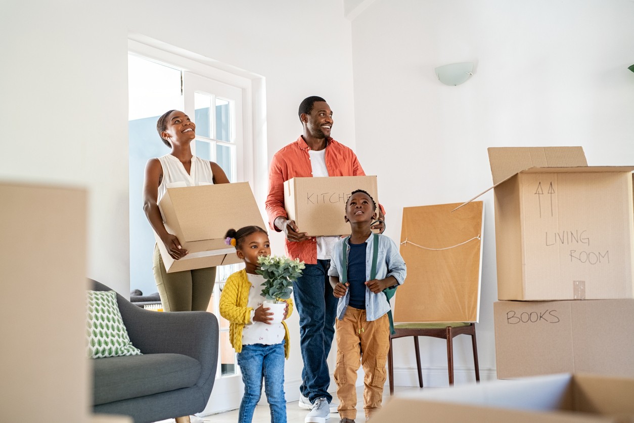 An African-American family carrying boxes as they move into their new home.